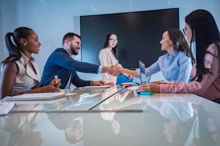 Colleagues shaking hands across a meeting room table