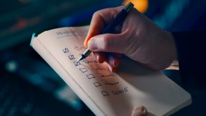 Hand checking off items on a to-do list, representing a monthly IT checklist