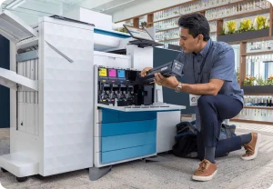 Technician loading toner into a large HP enterprise multifunction printer in an office