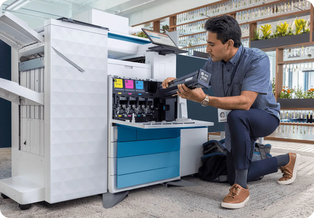 Technician loading toner into a large HP enterprise multifunction printer in an office